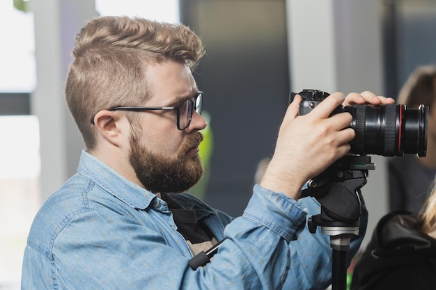 L'homme vidéaste travaille sur une caméra vidéo moderne de conférence de presse avec un affichage numérique enregistrant une interview sur l'événement Médias de masse et concept de télévision et de technologie