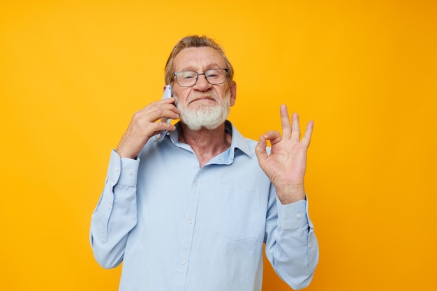 Homme vieil homme avec téléphone posant sur fond jaune