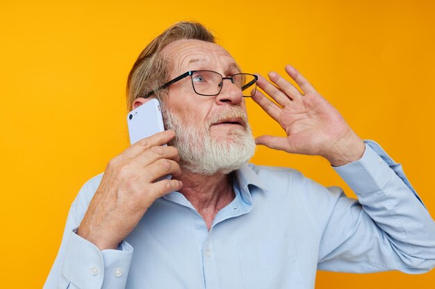 Homme vieil homme avec téléphone posant sur fond jaune