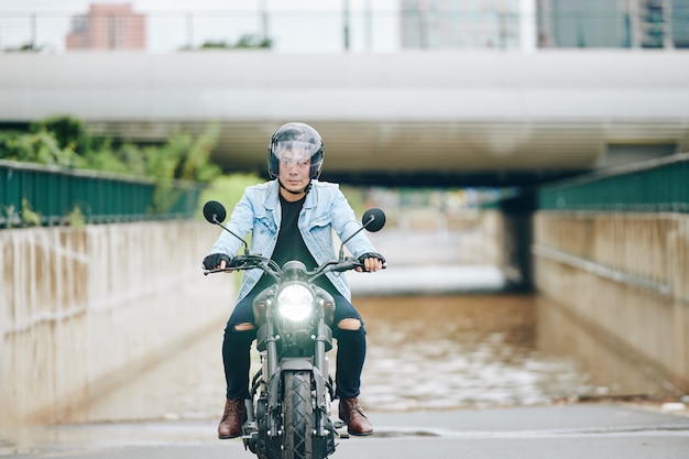 Homme vietnamien sérieux en casque à moto dans la ville