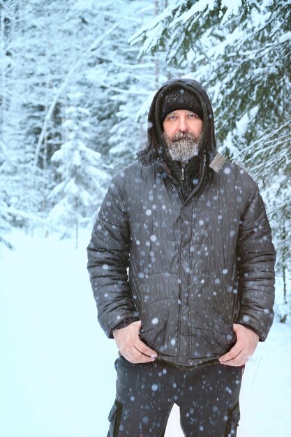 Homme avec visage gelé et barbe dans la forêt d'hiver en cas de gel sévère