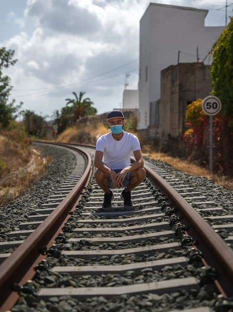L'homme sur la voie ferrée avec masque, T-shirt blanc et jeans