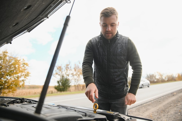 Homme avec voiture cassée au milieu de la route