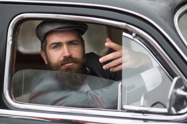 Homme en voiture rétro montrant un geste communicatif. Modèle masculin vintage