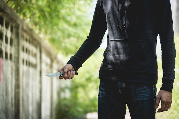 Homme de vol qualifié tenant un couteau, deux côtés de la forêt