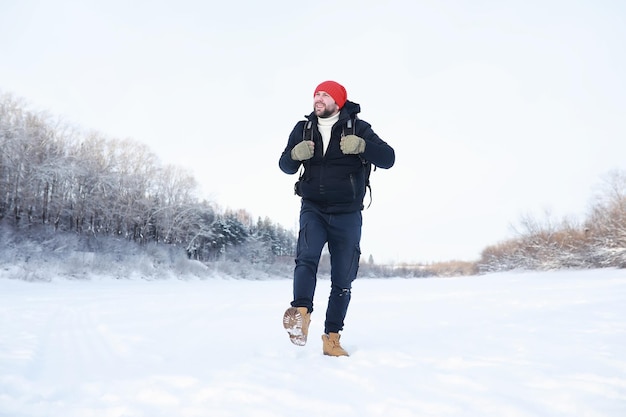 Un homme voyage avec un sac à dos. Randonnée hivernale en forêt. Touriste en promenade en hiver dans le parc.