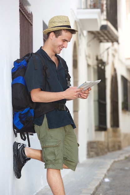 Homme de voyage souriant en regardant la carte à l&#39;extérieur