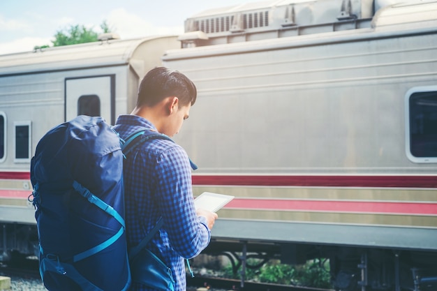 Homme voyageur à l&#39;aide de tablette et attend train sur la plate-forme ferroviaire