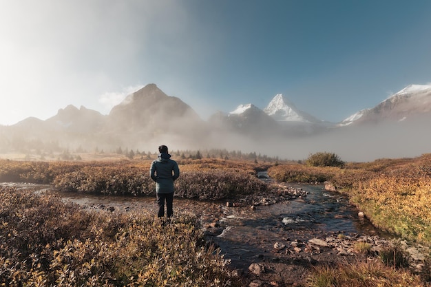 Homme de voyageur debout et regardant le mont Assiniboine dans le brouillard sur la forêt d'automne au parc provincial, Canada