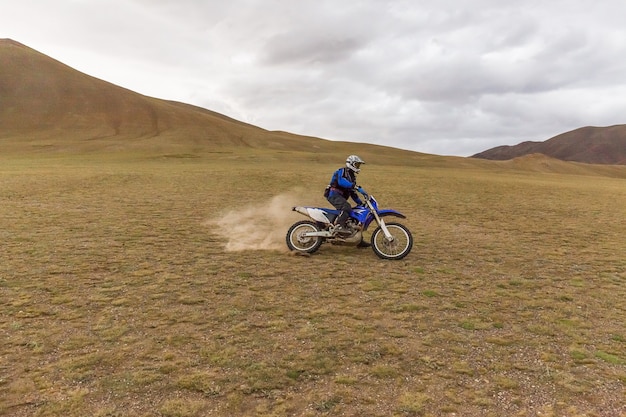 Homme de voyageur de moto en casque sur une moto dans les steppes de la Mongolie.