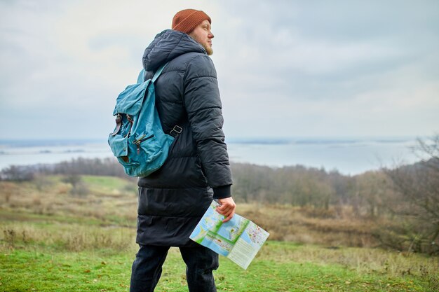 Homme voyageur avec sac à dos avec carte à la main sur un mur de montagnes rivière de la nature, concept de voyage, vacances et concept de randonnée de style de vie