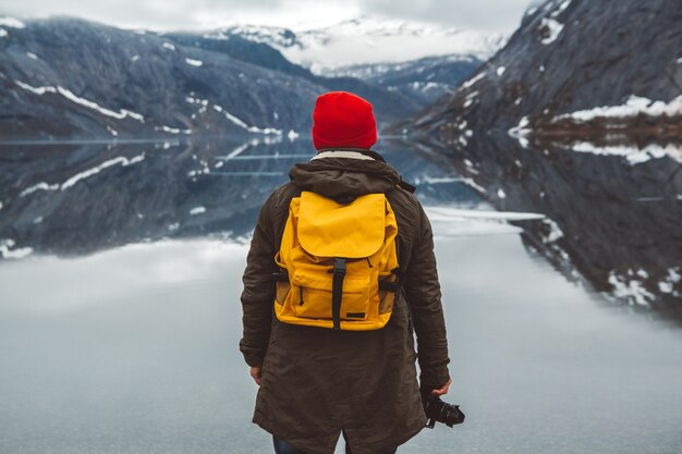 Homme de voyageur avec un sac à dos debout sur le fond des montagnes et du lac, profitant du paysage