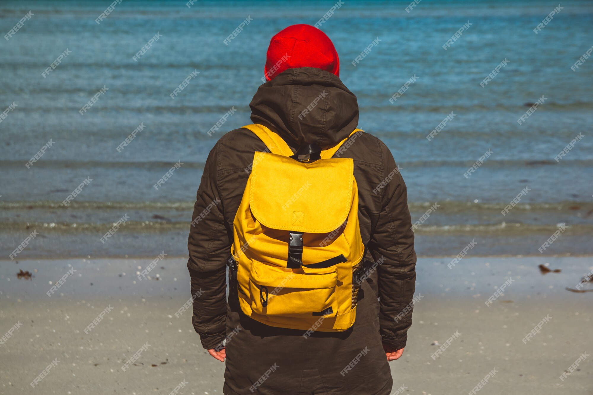 Homme De Voyageur Avec Un Sac à Dos Jaune Debout Sur Une Plage De Sable Sur  Fond De Mer