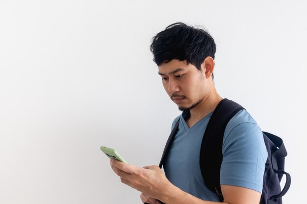 Homme voyageur avec un sac à dos utilise une application de téléphonie mobile.