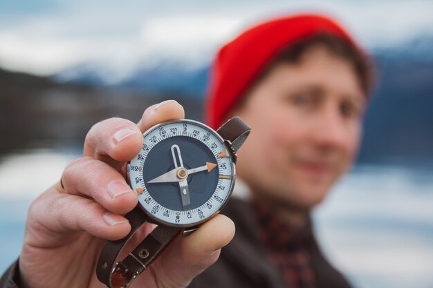 L'homme de voyageur tient une vieille boussole dans la perspective de la montagne et d'un lac