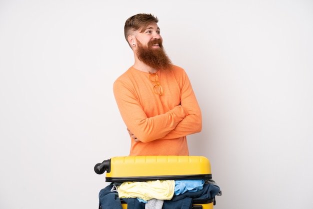 Homme voyageur avec une valise pleine de vêtements sur rire blanc isolé