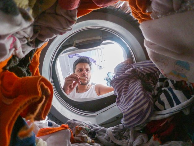 Photo homme vu à travers la porte par le linge dans la machine à laver