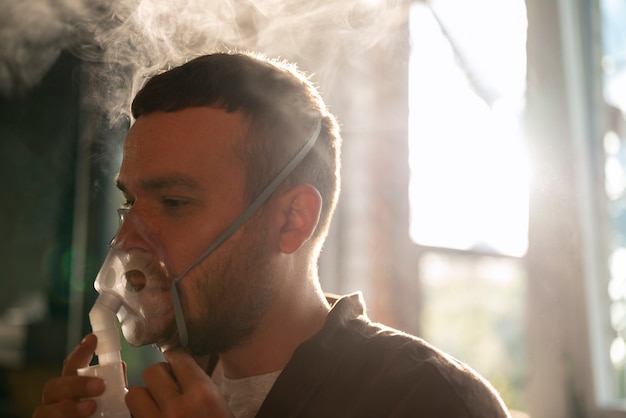 Photo homme vue de côté à l'aide d'un nébuliseur