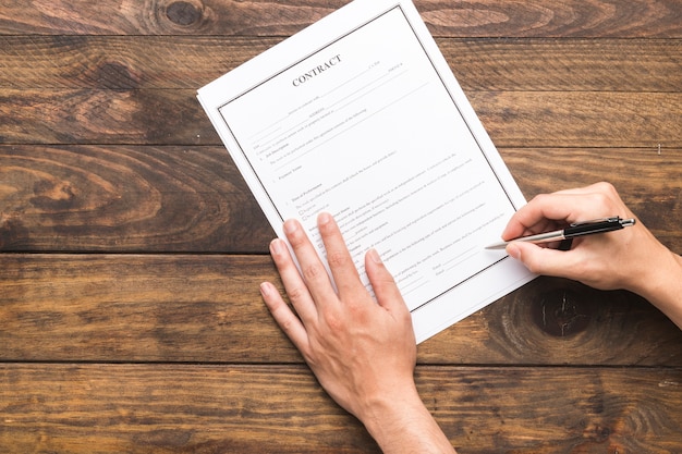 Homme vue de dessus, signature d'un contrat sur une table en bois