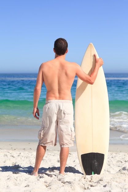 Homme wirth sa planche de surf sur la plage