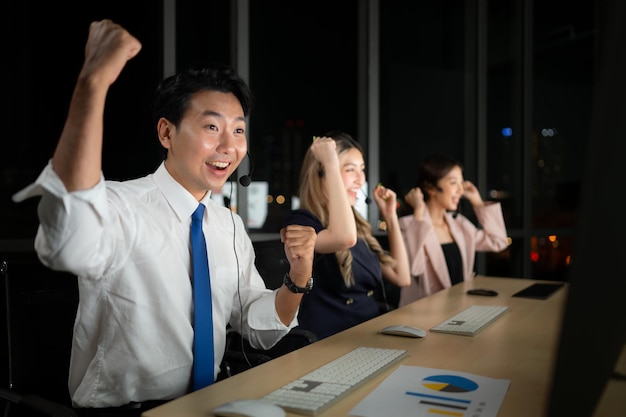 Des hommes d'affaires asiatiques prospères célèbrent leur succès au bureau la nuit.