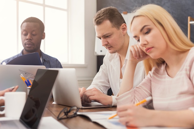 Des hommes d'affaires concentrés travaillant au bureau. Jeune équipe occupée à étudier un nouveau projet ou un rapport financier, espace de copie