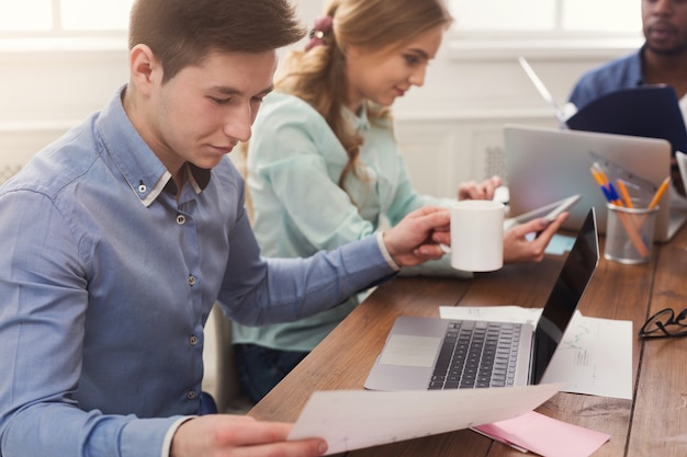 Des hommes d'affaires concentrés travaillant au bureau. Jeune équipe occupée à étudier un nouveau projet ou un rapport financier, espace de copie