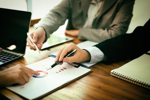 Des hommes d'affaires discutant sur un graphique assis sur une table.