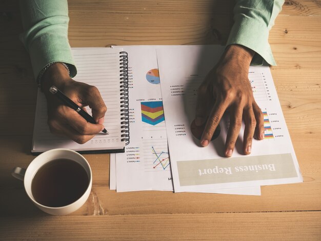 Les hommes d&#39;affaires écrivent, les cartes de papier et la tasse de café sur la table.