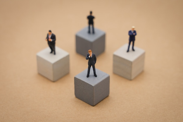 Hommes d&#39;affaires miniature 4 personnes debout sur un cube en bois Analyse d&#39;investissement