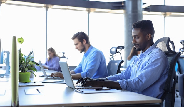 Hommes d'affaires modernes analysant les données boursières tout en travaillant au bureau.