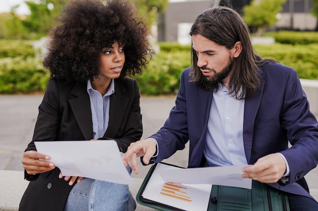 Hommes d'affaires multiethniques analysant des statistiques à l'extérieur du bureau