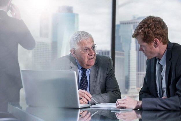 Des hommes d'affaires avec un ordinateur portable discutant au bureau.