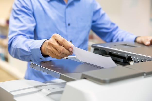 Photo hommes d'affaires placez les papiers sur le copieur pour copier et numériser les documents papier dans le bureau.