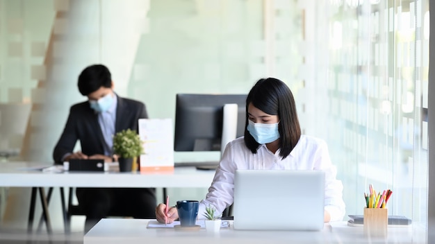 Hommes d'affaires portant un masque de protection travaillant dans un bureau moderne.