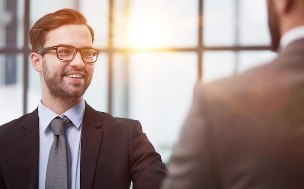 Des hommes d'affaires souriants se serrent la main pour commencer un partenariat d'équipe debout dans le couloir de l'espace de travail de l'entreprise.