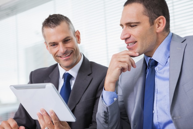 Hommes d&#39;affaires souriants travaillant ensemble sur leur tablette