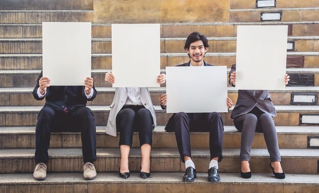 Des hommes d'affaires tenant un papier blanc alors qu'ils sont assis sur des marches