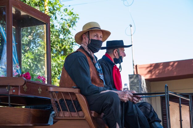 Photo des hommes âgés à cheval sur une charrette antique lors d'un festival sud-américain.