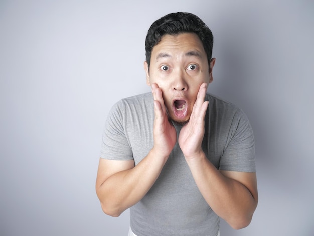 des hommes asiatiques en chemise grise décontractée geste choqué avec la bouche ouverte les mains levées