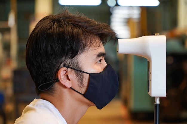 Les hommes asiatiques utilisent des thermomètres infrarouges numériques pour mesurer la température corporelle avec la paume de leurs mains les hommes au point de contrôle COVID19 enregistrés avant d'entrer dans l'usine