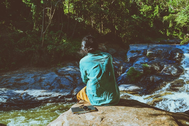 Les hommes asiatiques voyagent la nature. Étude lire un livre. Nature Education Ecrire une note At Waterfall