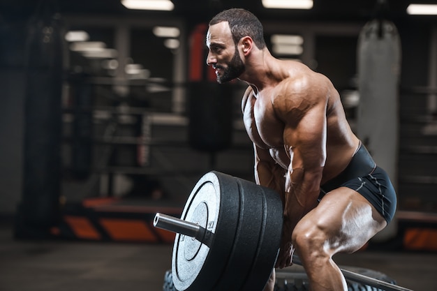 Hommes athlétiques bodybuilder forts brutaux pompant les muscles avec des haltères