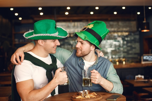 Photo les hommes aux chapeaux verts. des amis célèbrent la saint-patrick. célébration dans un pub.