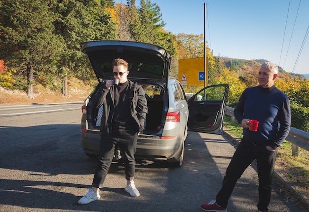 Les hommes boivent du café ou du thé sur le bord de la route.