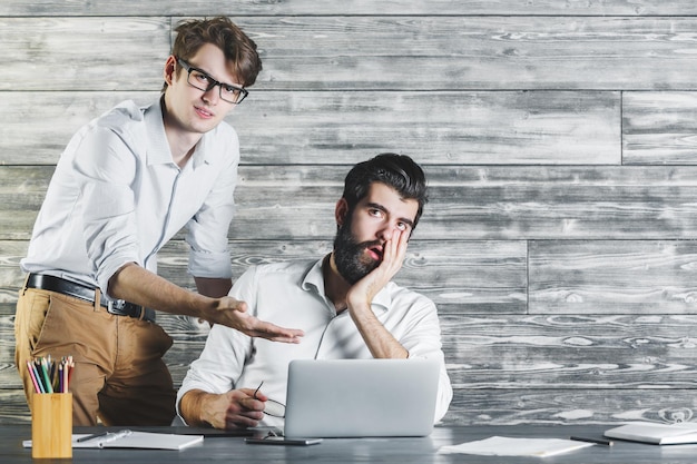 Hommes fatigués utilisant un ordinateur portable