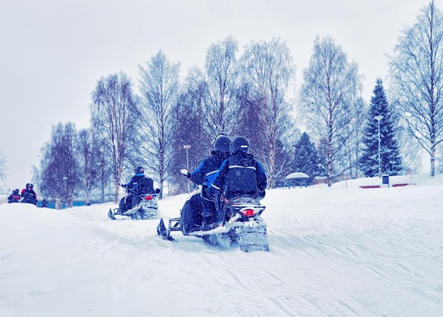 Hommes et femmes faisant de la motoneige en hiver Rovaniemi, Laponie, Finlande