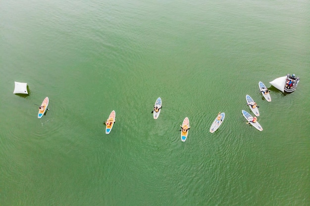 Des hommes forts flottant sur des planches de SUP dans une magnifique baie par une journée ensoleillée Vue aérienne des hommes traversant la baie à l'aide du paddleboard Compétitions de sports nautiques