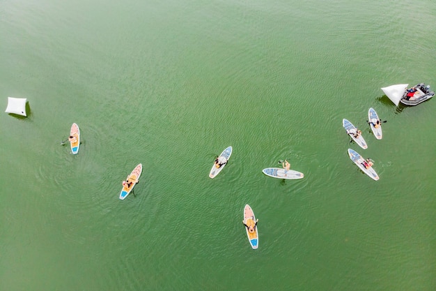 Des hommes forts flottant sur des planches de SUP dans une magnifique baie par une journée ensoleillée Vue aérienne des hommes traversant la baie à l'aide du paddleboard Compétitions de sports nautiques