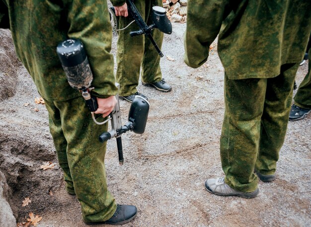 Hommes avec des fusils jouant au paintball. En plein air